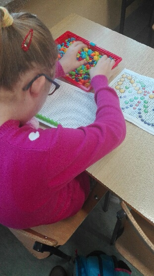 Dziecko używające maty do tworzenia kształtów z kolorowych pinów